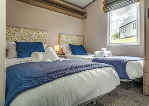 Een hotelkamer met twee bedden, een raam met uitzicht en een hoofdeinde met bloemenmotief.