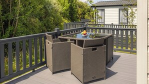 An outdoor deck with wicker furniture and a table, surrounded by a wooden deck and a fence. - 1 bedroom accommodation in Mawgan Porth, Nr Newquay (Mawgan Porth, Nr Newquay)