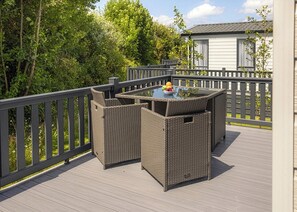 An outdoor deck with wicker furniture and a table, surrounded by a wooden deck and a fence. - 1 bedroom accommodation in Mawgan Porth, Nr Newquay (Mawgan Porth, Nr Newquay)