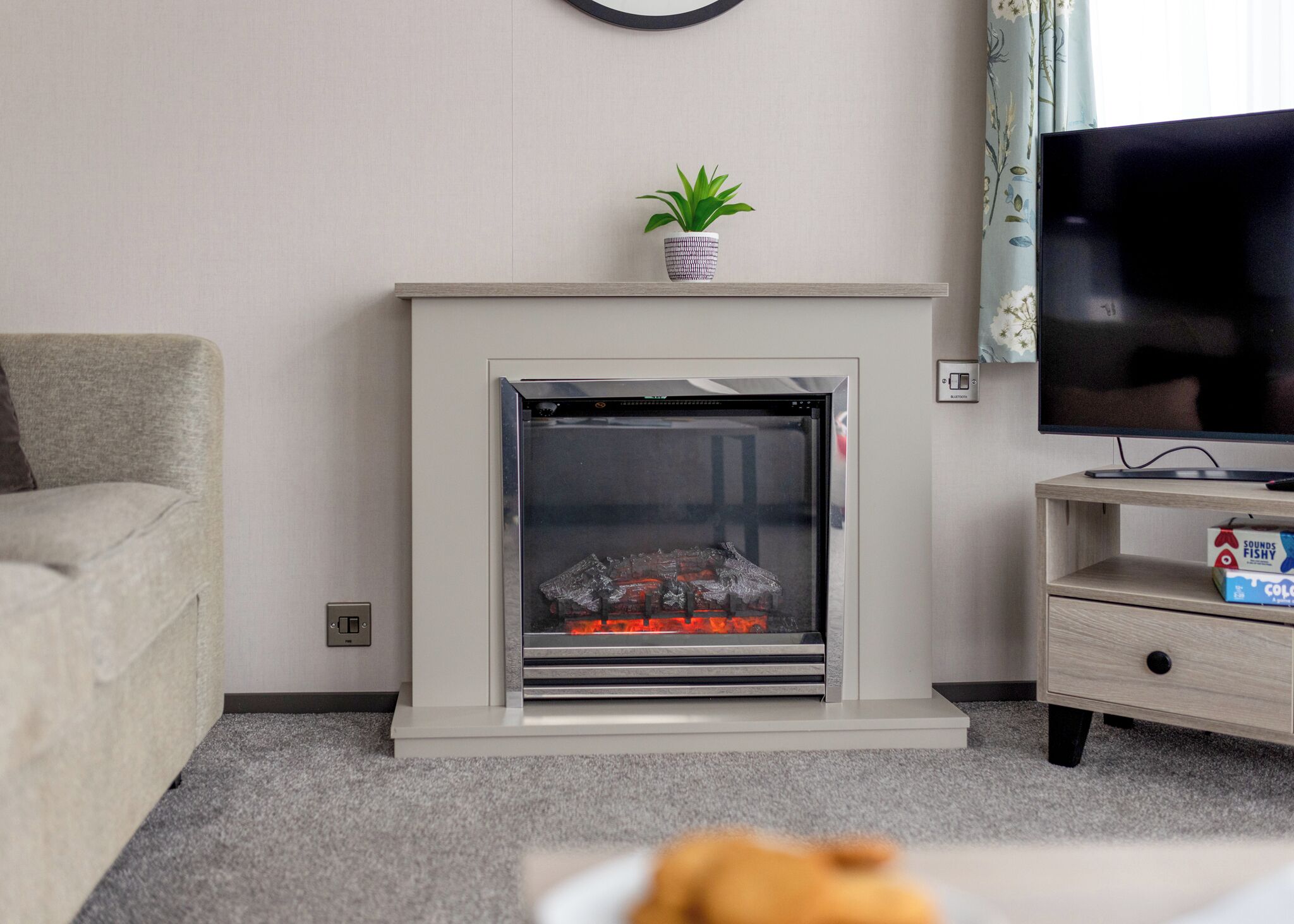 A living room with a fireplace, a television, a sofa, and a small table with a box.