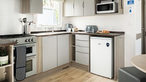 A compact kitchen with a stove, oven, microwave, and a small refrigerator. - Standard 2 Bed (Pet) (Mawgan Porth, Nr Newquay)