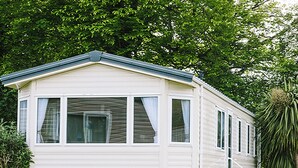 A single-story mobile home with a flat roof, large windows, and a ramp for accessibility. - Standard 2 Bed (Pet) (Mawgan Porth, Nr Newquay)