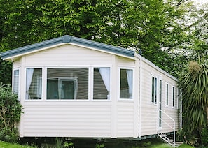 A single-story mobile home with a flat roof, large windows, and a ramp for accessibility. - Standard 2 Bed (Pet) (Mawgan Porth, Nr Newquay)