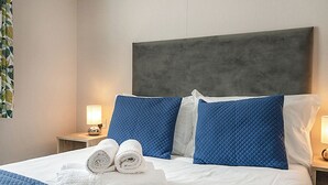 A hotel room with a large bed, two pillows, a headboard, and two bedside lamps. - Standard 2 Bed (Pet) (Mawgan Porth, Nr Newquay)