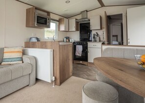 A compact RV kitchen with a microwave, stove, and sink. - The Superior 2 Bedroom is a comfortable and spacious sleeps 6 caravan. (Mawgan Porth, Nr Newquay)