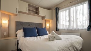 Una camera d'albergo con un letto grande, due comodini, una testiera e una finestra con tende.