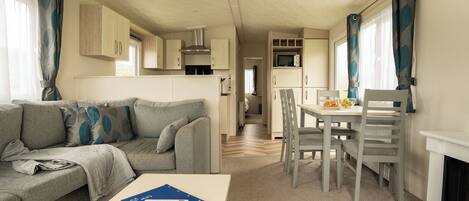 Ein gemütlicher Wohnbereich mit Sofa, Esstisch mit Stühlen, Mikrowelle und Kamin.