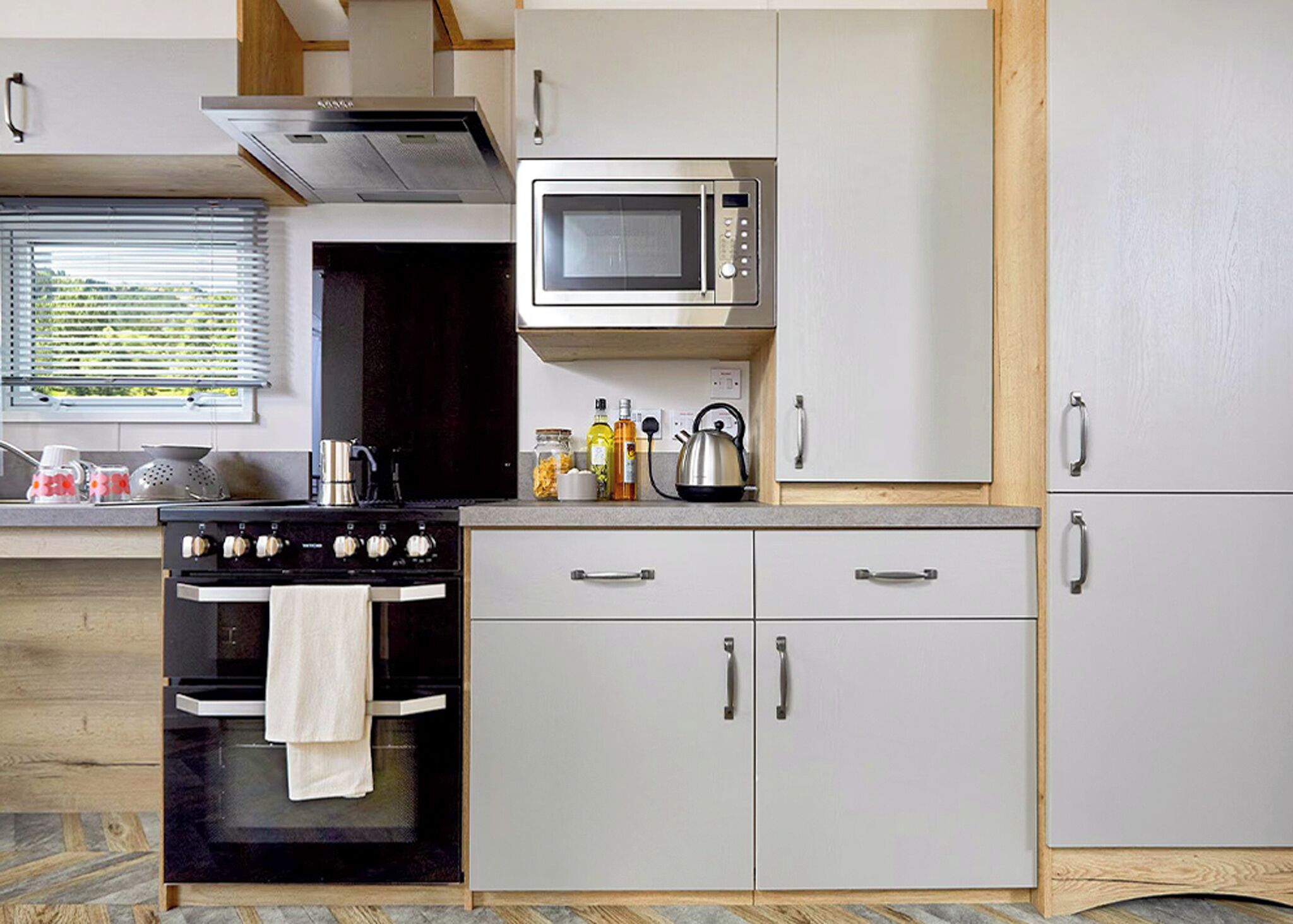Une cuisine de taille réduite, équipée d’une cuisinière, d’un four à micro-ondes et de placards.
