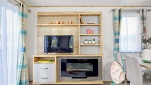 Een kamer met een televisie, houten planken, een openhaard, een bureau en een stoel.
