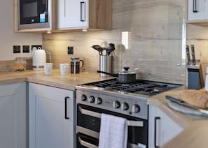 Eine moderne Küche mit Edelstahlgeräten, Holzschränken und einer eingebauten Mikrowelle.