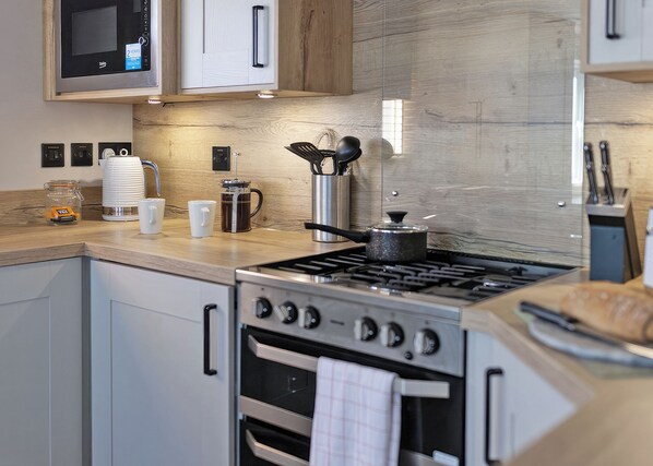 Una cocina moderna con electrodomésticos de acero inoxidable, armarios de madera y microondas integrado.