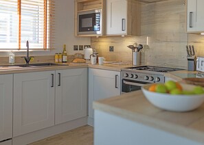 Una cocina moderna con microondas integrado, electrodomésticos de acero inoxidable y encimera de madera.