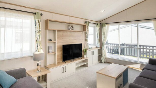 Un salon moderne doté d’un téléviseur à écran plat, d’étagères en bois, d’un canapé et offrant une vue sur le balcon.