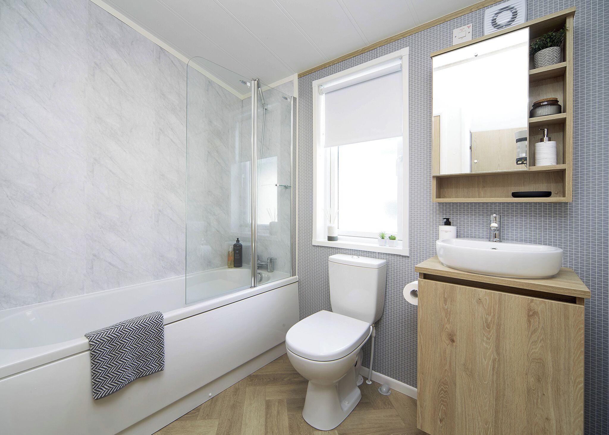 A modern bathroom with a glass-enclosed shower, a toilet, a sink, and a window.