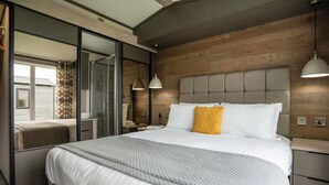 Une chambre moderne avec un grand lit, un miroir, des tables de chevet et un mur en bois.