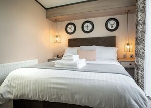 Ein Hotelzimmer mit einem großen Bett, einem Kopfteil, Nachttischen, Wandkunst und einem gemusterten Vorhang.