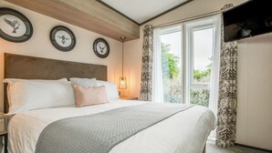 A bedroom with a bed, bedside tables, a window with curtains, and wall-mounted artwork. - 1 bedroom accommodation in Padstow (Padstow)