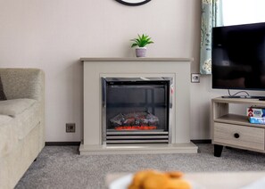 A living room with a fireplace, a television, a sofa, and a small table with a box. - 1 bedroom accommodation in Padstow (Padstow)