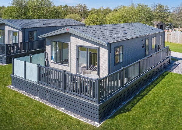 A modern mobile home with a balcony, large windows, and a flat roof.