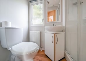 Un baño pequeño con inodoro, lavamanos y ducha.