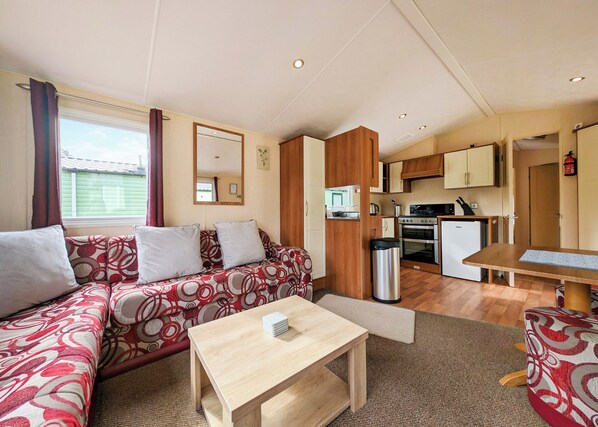 A compact living space with a sofa, a small table, a kitchenette, and a dining area.