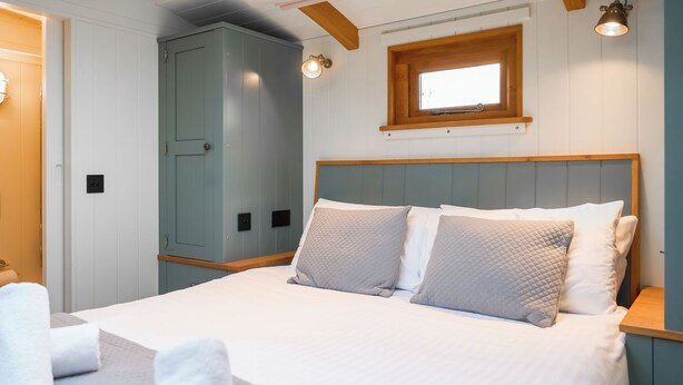 A bedroom with a bed, pillows, a wardrobe, and a window. - 1 bedroom accommodation in Landford, Nr Salisbury (Landford, Nr Salisbury)