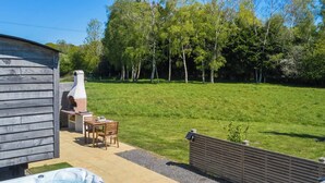 A backyard with a hot tub, barbecue grill, and wooden deck. - 1 bedroom accommodation in Landford, Nr Salisbury (Landford, Nr Salisbury)