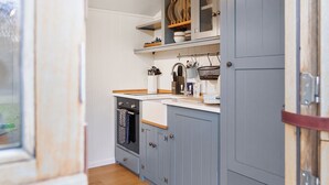 A kitchen with wooden cabinets, a countertop, and a window. - 1 bedroom accommodation in Landford, Nr Salisbury (Landford, Nr Salisbury)