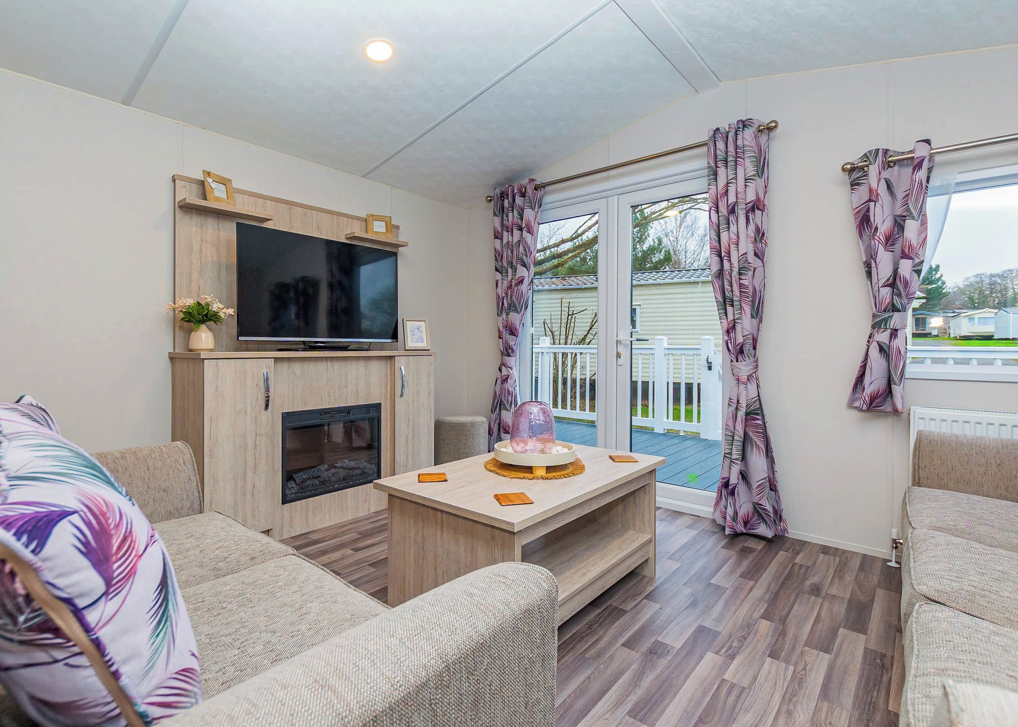 A modern living room with a flat-screen TV, fireplace, and a dining area with a table and chairs.