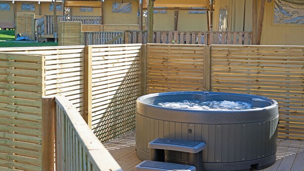 Un bain à remous doté d’une terrasse en bois et d’un espace abrité sous une auvent.