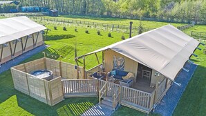 A wooden cabin with a deck, a hot tub, and a covered seating area. - The Woody Safari Tent (Pet) (Landford, Nr Salisbury)