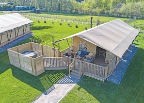 A wooden cabin with a deck, a hot tub, and a covered seating area.