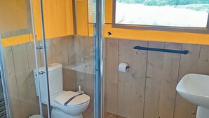 Une petite salle de bain compacte, équipée de toilettes, d’un lavabo et d’un espace douche.