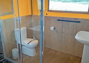 A small, compact bathroom with a toilet, sink, and shower enclosure. - The Woody Safari Tent (Pet) (Landford, Nr Salisbury)