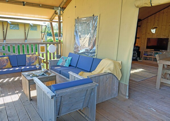 A wooden deck with a blue sofa, a wooden table, and a television in a room.