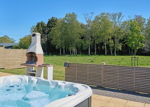 A hot tub, outdoor grill, and a fenced yard with trees. - 1 bedroom accommodation in Landford, Nr Salisbury (Landford, Nr Salisbury)