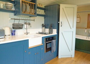 A kitchen with blue cabinets, a white door, and a wooden floor. - 1 bedroom accommodation in Landford, Nr Salisbury (Landford, Nr Salisbury)