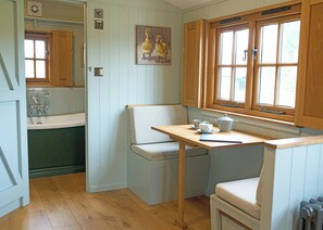 A kitchen with wooden cabinets, a window, a painting of ducks, and a table with a kettle and cups. - 1 bedroom accommodation in Landford, Nr Salisbury (Landford, Nr Salisbury)