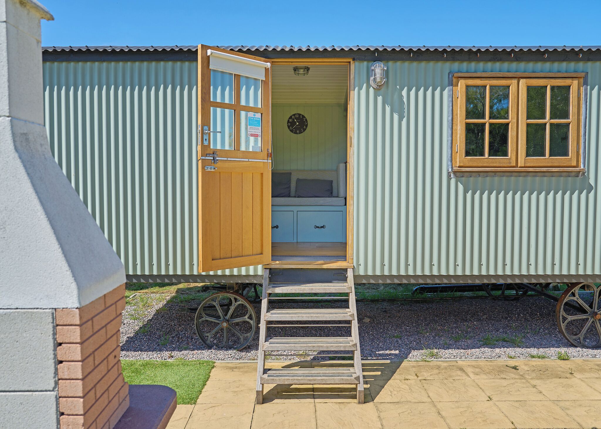 A small, single-story building with a wooden door leading to a room with a bed and a small desk.