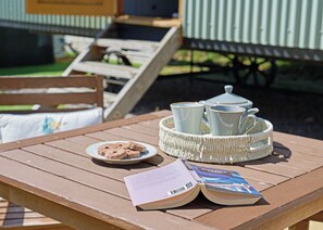 Une table en bois, un livre, un plateau avec des tasses à thé et une assiette de biscuits.