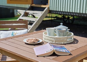 A wooden table with a book, a tray with teacups, and a plate of cookies. - 1 bedroom accommodation in Landford, Nr Salisbury (Landford, Nr Salisbury)