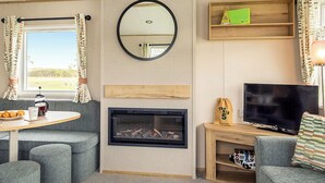Ein gemütliches Wohnzimmer mit Kamin, Fernseher, Couchtisch und einer Couch.