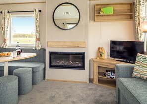 Ein gemütliches Wohnzimmer mit Kamin, Fernseher, Couchtisch und einer Couch.