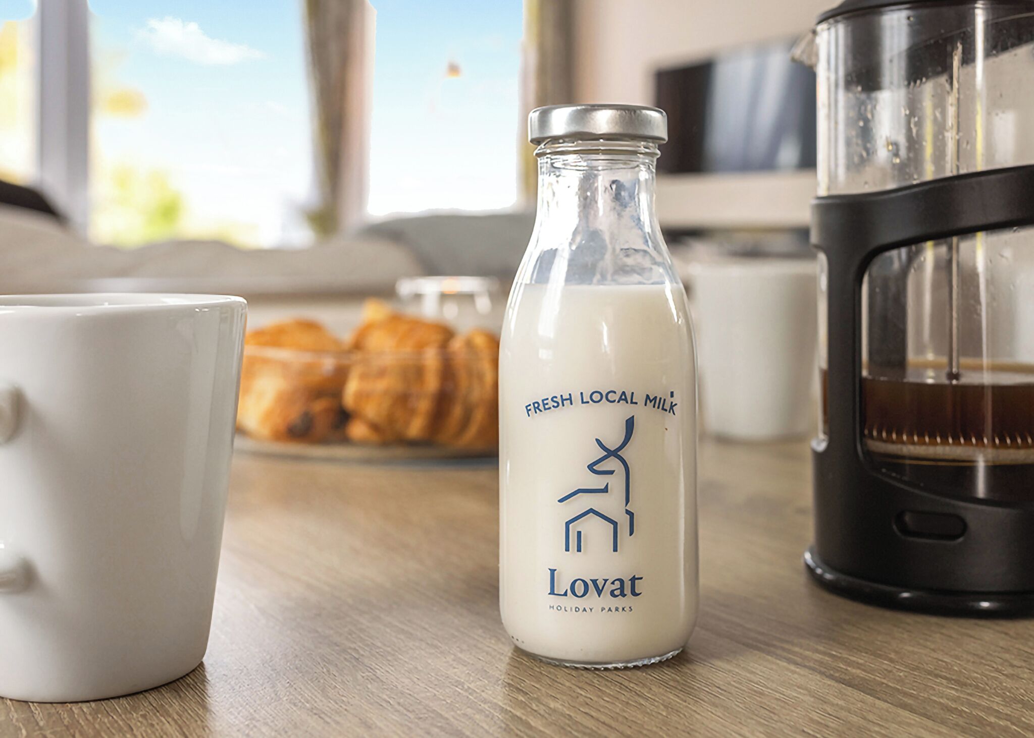 Een fles melk, een koffiezetapparaat en een kopje op een houten tafel.