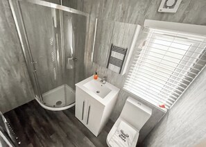 Une salle de bain moderne avec une douche à parois de verre, un lavabo blanc et des toilettes.