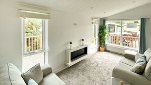 Un salon moderne doté d’une cheminée, de grandes fenêtres et d’un balcon.