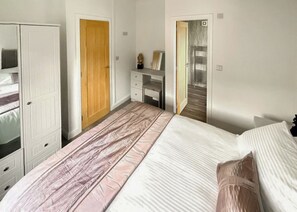 A bedroom with a bed, a wardrobe, a desk, and a mirror.