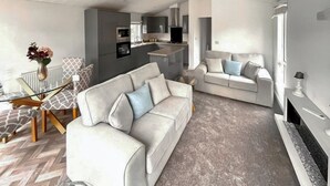 Un salon moderne avec un canapé, une table basse et une cheminée.