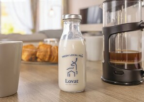 A bottle of fresh local milk, a coffee maker, and pastries on a wooden table. - Superior 3 Bed (Pet) (Great Yarmouth)