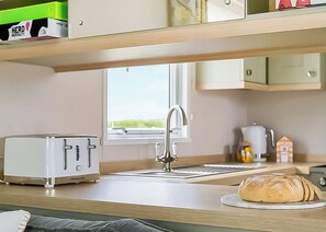 Eine Küchenzeile mit Toaster, Spüle, Fenster und einem Brotlaib auf der Arbeitsfläche.